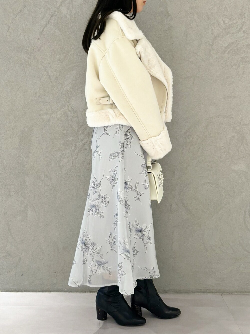 パープル系のワンピース、ブラック系のブーツ、ホワイト系のショルダーバッグを着用したレディースの秋コーディネートの4枚目の写真