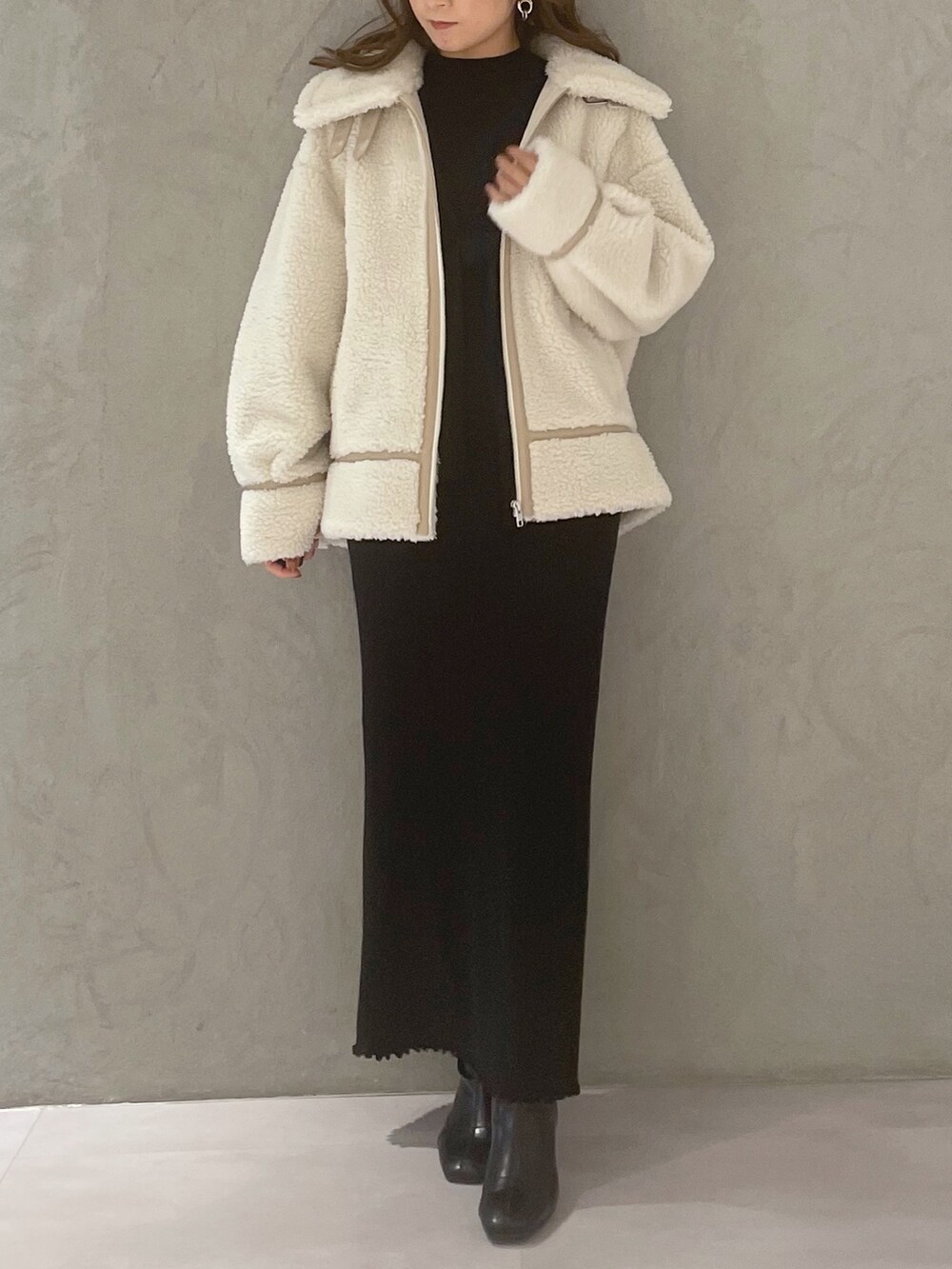 ブラック系のワンピース、ホワイト系のその他アウター、ブラック系のブーツを着用したレディースの冬コーディネートの4枚目の写真