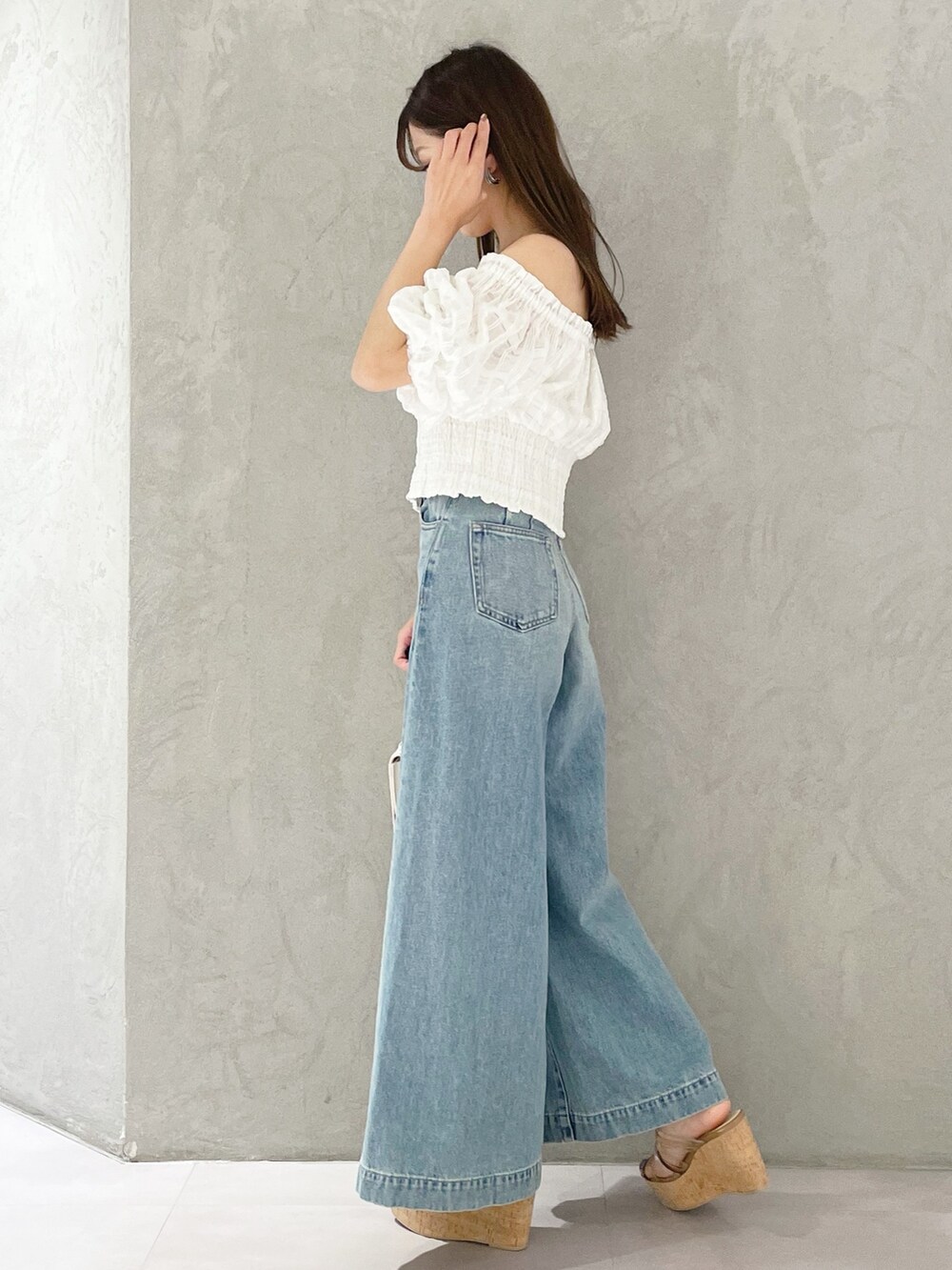 ブルー系のデニムパンツ、ブラウン系のサンダル、ホワイト系のハンドバッグを着用したレディースの春コーディネートの4枚目の写真