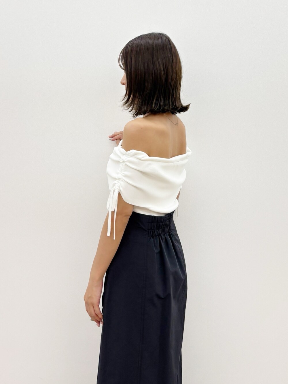 ブラック系のスカート、ホワイト系のニット/セーターを着用したレディースの夏コーディネートの9枚目の写真