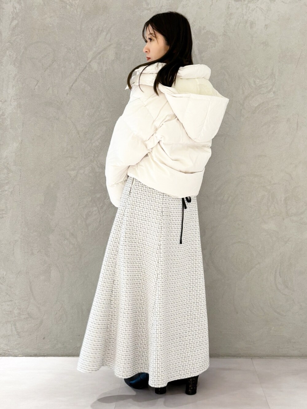 ホワイト系のスカート、ブラック系のブーツ、ホワイト系のハンドバッグを着用したレディースの冬コーディネートの7枚目の写真