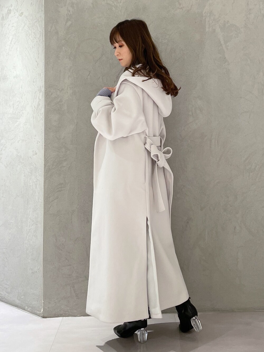 ブルー系のニット/セーター、ブラック系のスカート、ホワイト系のチェスターコートを着用したレディースの冬コーディネートの5枚目の写真