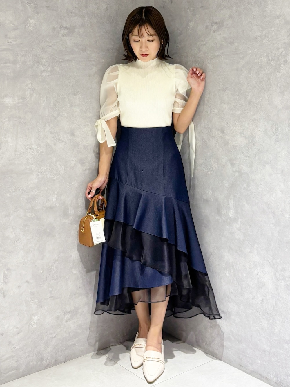 ブルー系のスカート、ホワイト系のニット/セーター、ホワイト系のパンプスを着用したレディースの春コーディネートの6枚目の写真