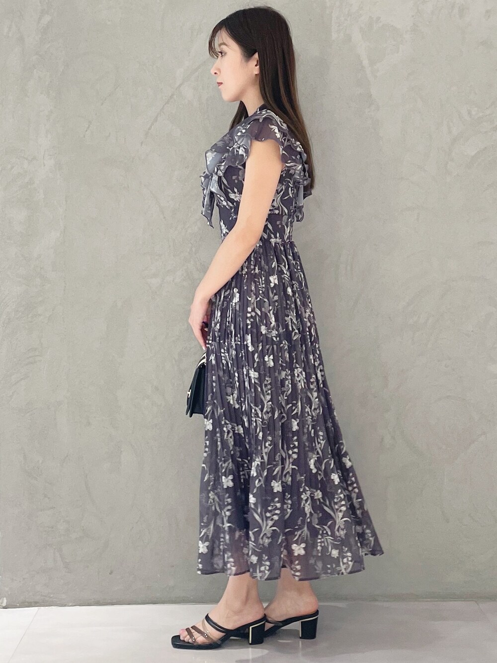 ブラック系のハンドバッグ、ブラック系のサンダル、グレー系のワンピースを着用したレディースの春コーディネートの3枚目の写真