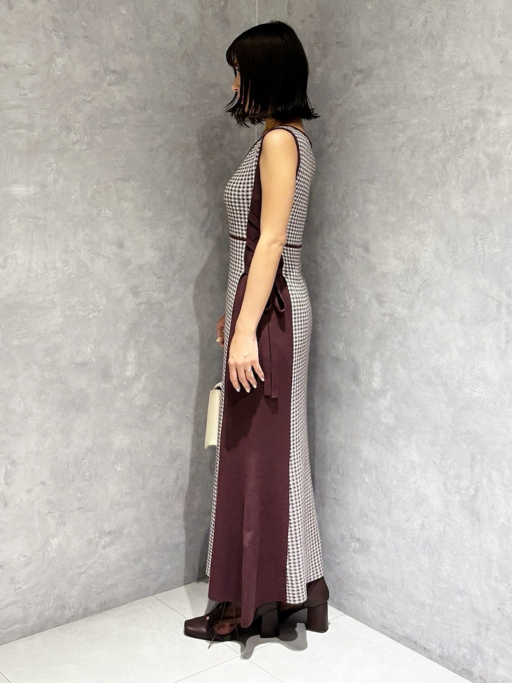 ブラウン系のワンピース、ブラウン系のブーツ、ホワイト系のハンドバッグを着用したレディースの夏コーディネートの2枚目の写真