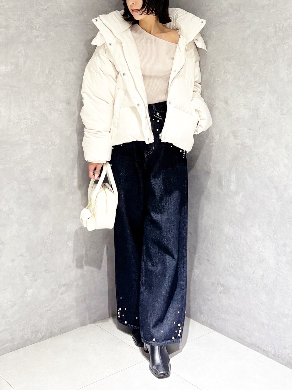 ブルー系のデニムパンツ、ホワイト系のダウンジャケット/コート、ベージュ系のニット/セーターを着用したレディースの秋コーディネートの5枚目の写真