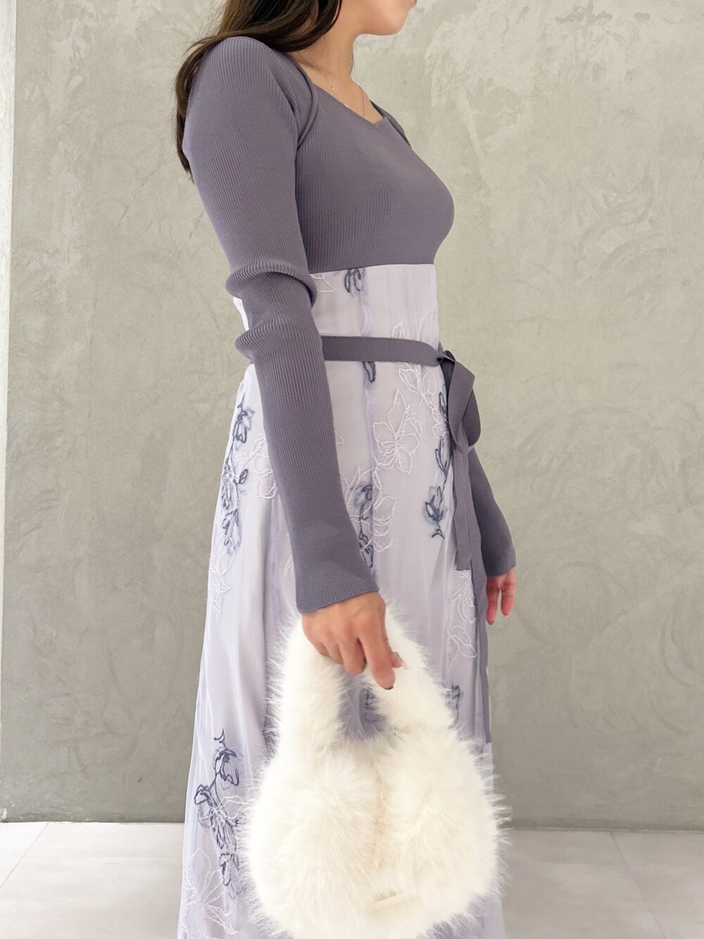 パープル系のワンピース、ブラック系のブーツ、ホワイト系のハンドバッグを着用したレディースの秋コーディネートの2枚目の写真