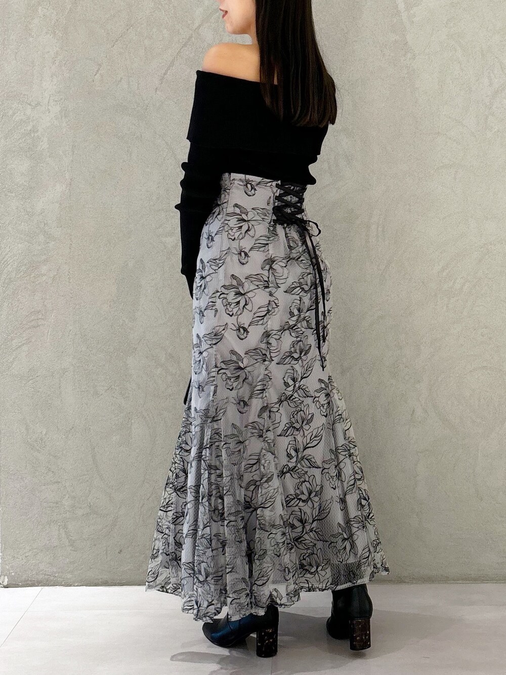 グレー系のスカート、ブラック系のブーツ、ブラック系のショルダーバッグを着用したレディースの秋コーディネートの5枚目の写真