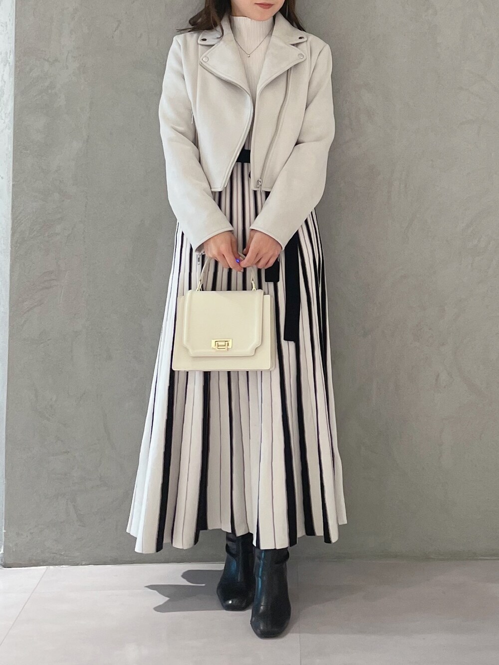 ホワイト系のワンピース、ピンク系のライダースジャケット、ホワイト系のハンドバッグを着用したレディースの春コーディネートの6枚目の写真