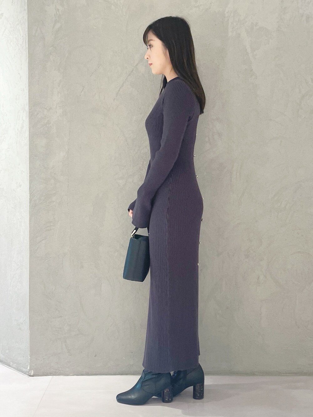 ブラック系のハンドバッグ、ブラック系のブーツ、グレー系のワンピースを着用したレディースの冬コーディネートの2枚目の写真