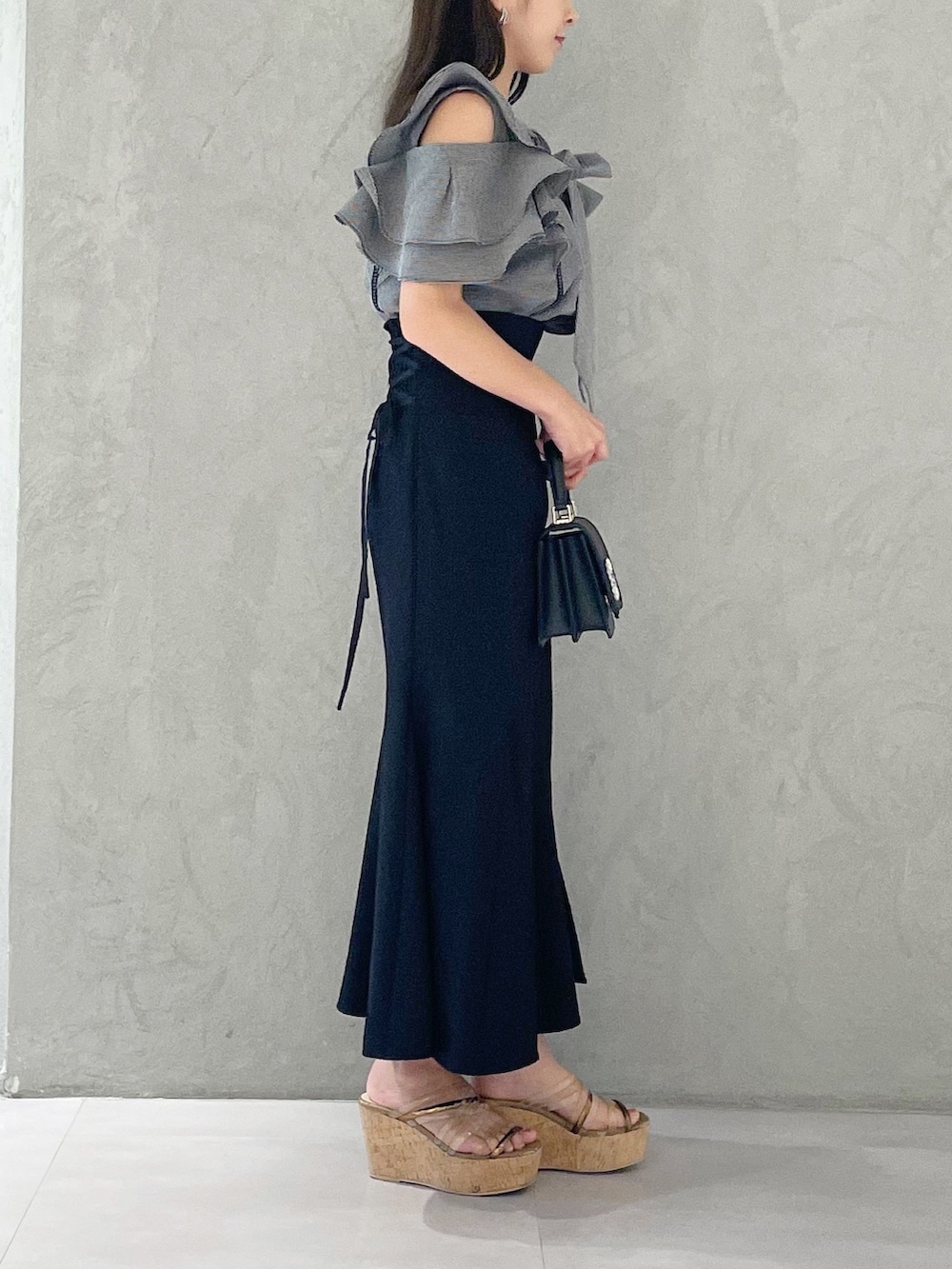 ブラック系のスカート、ブラウン系のサンダル、ブラック系のショルダーバッグを着用したレディースの夏コーディネートの2枚目の写真