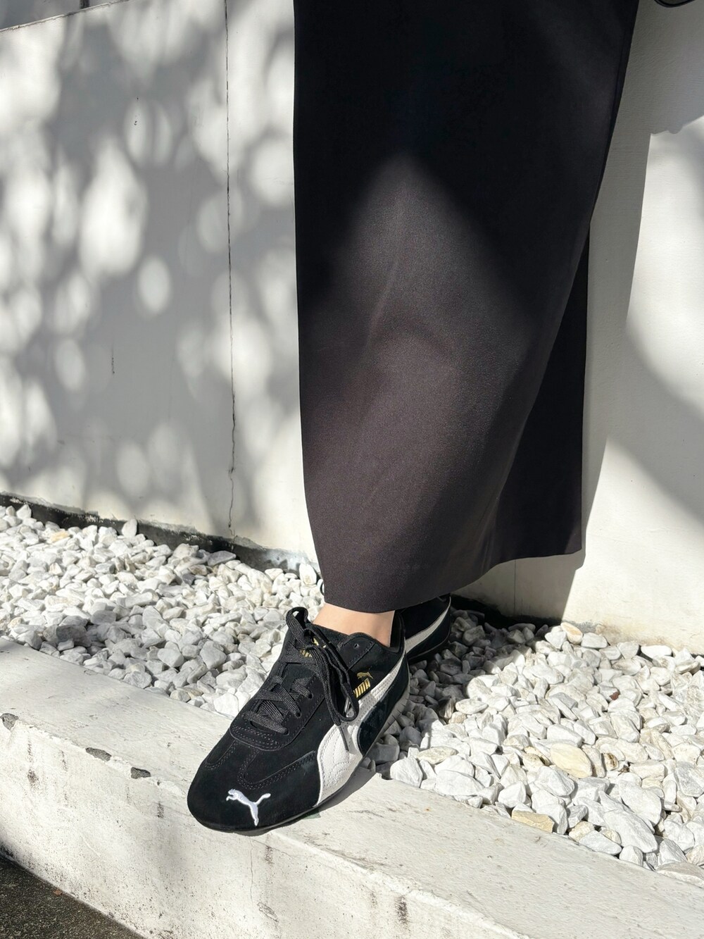 ブラック系のスカート、ブラック系のスニーカー、グレー系のニット/セーターを着用したレディースの秋コーディネートの2枚目の写真