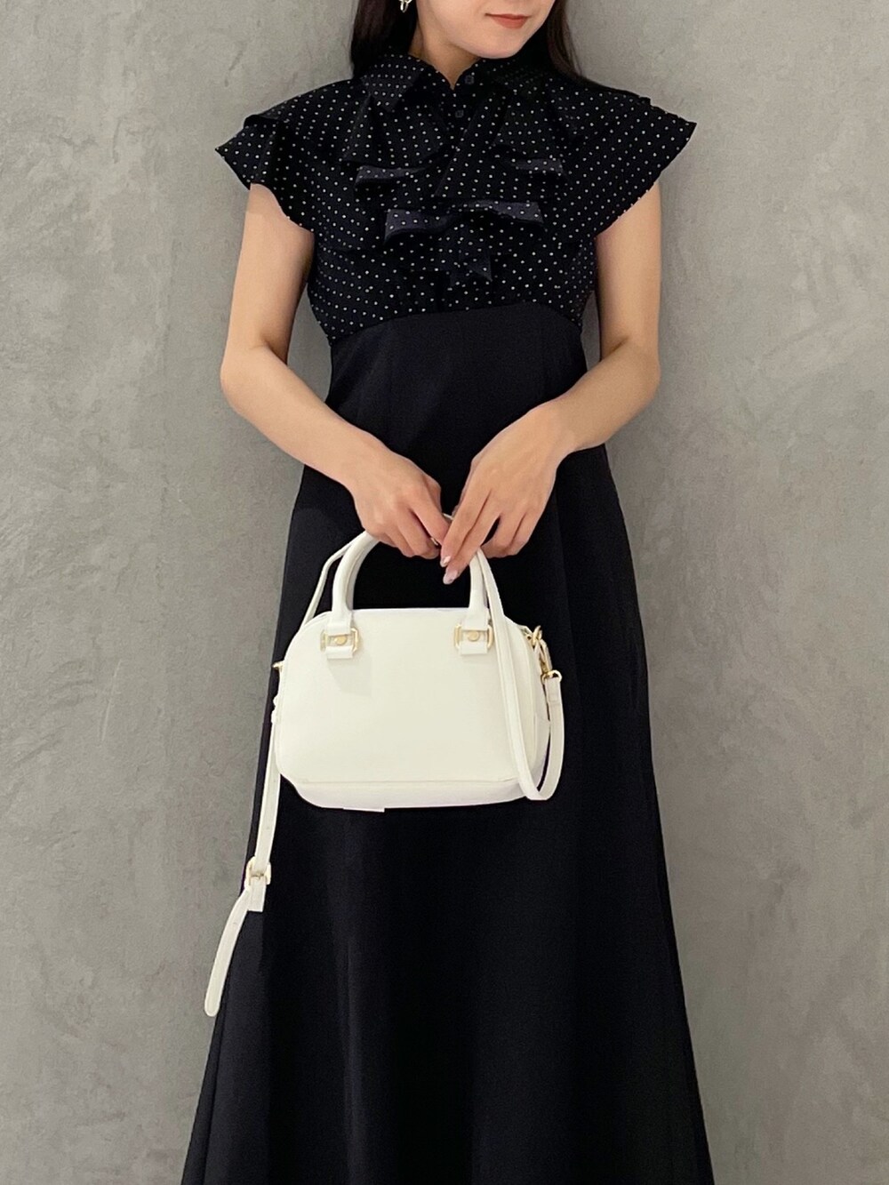 ブラック系のワンピース、ホワイト系のボストンバッグ、ブラック系のサンダルを着用したレディースの春コーディネートの4枚目の写真