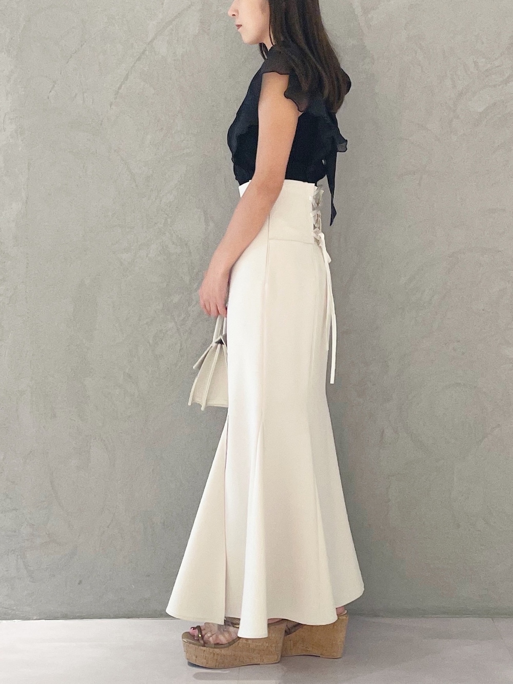 ブラック系のニット/セーター、ホワイト系のスカート、ブラウン系のサンダルを着用したレディースの夏コーディネートの2枚目の写真