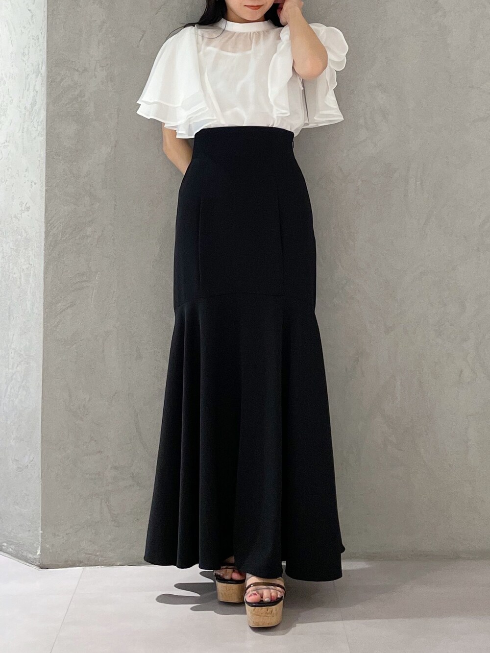 ブラック系のスカート、ブラック系のサンダル、ホワイト系のシャツ/ブラウスを着用したレディースの春コーディネートの6枚目の写真