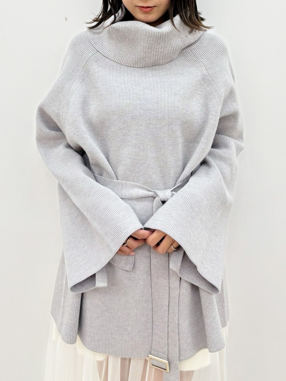 グレー系のニット/セーター、グレー系のブーツ、ホワイト系のスカートを着用したレディースの秋コーディネートの3枚目の写真