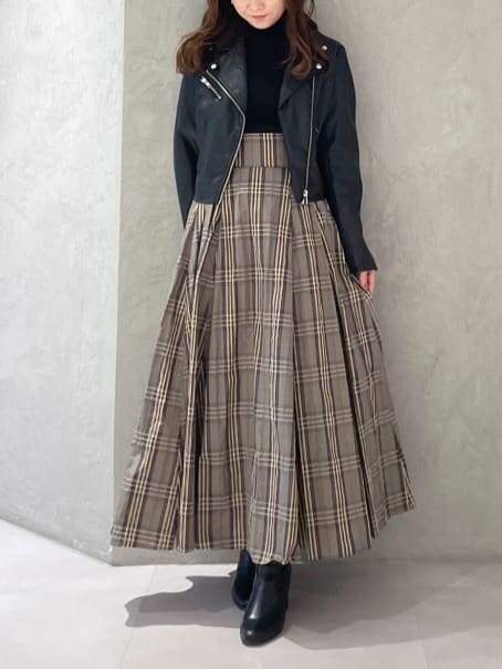 ブラック系のライダースジャケット、ブラック系のニット/セーター、ベージュ系のスカートを着用したレディースの秋コーディネートの2枚目の写真