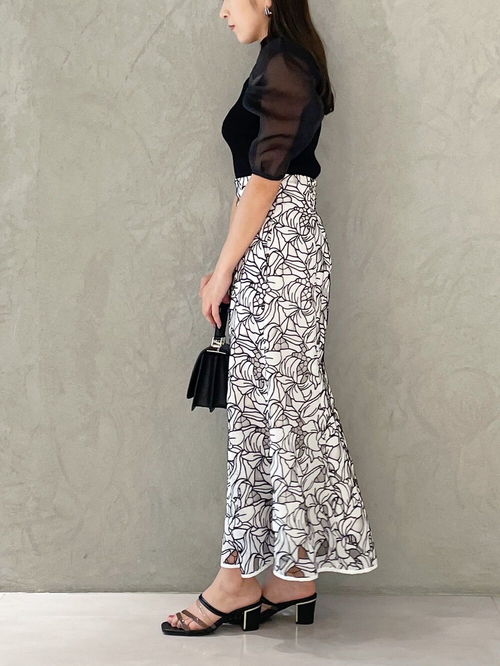 ホワイト系のスカート、ブラック系のサンダル、ブラック系のショルダーバッグを着用したレディースの夏コーディネートの2枚目の写真