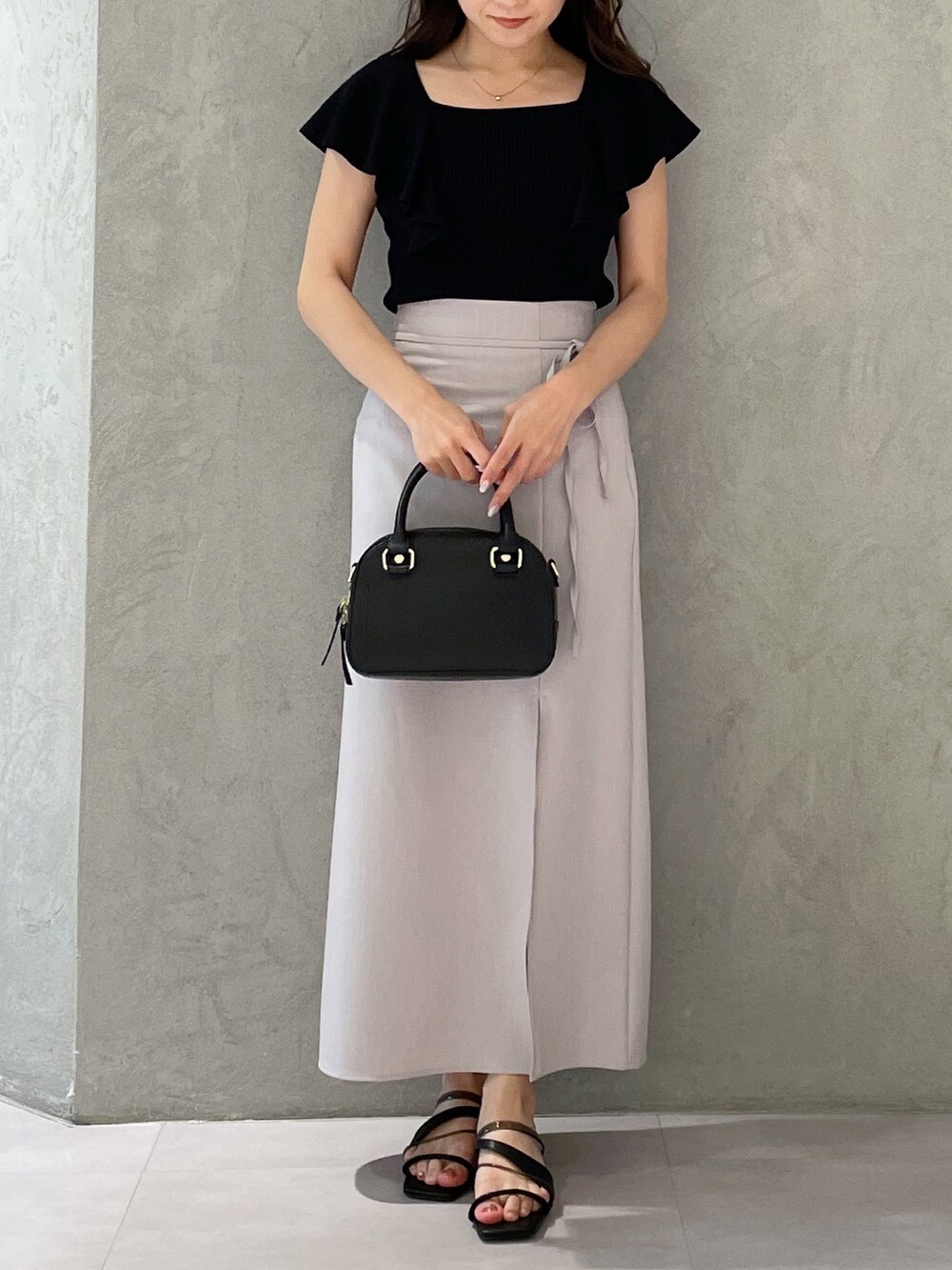 ブラック系のボストンバッグ、ブラック系のニット/セーター、ブラック系のサンダルを着用したレディースの春コーディネートの8枚目の写真