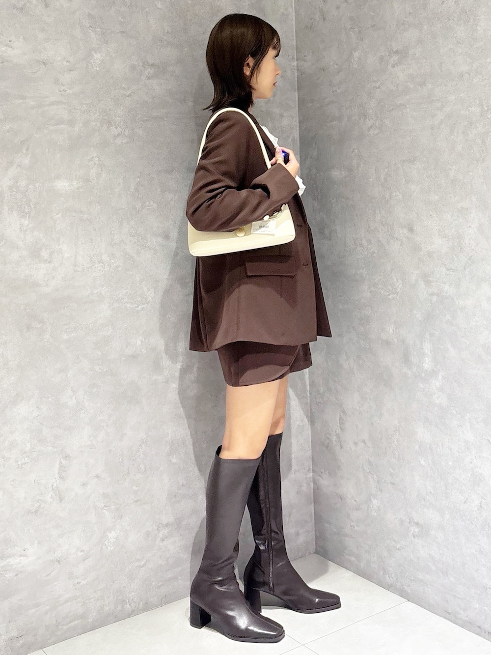 ホワイト系のシャツ/ブラウス、ホワイト系のハンドバッグ、ブラウン系のブーツを着用したレディースの春コーディネートの4枚目の写真