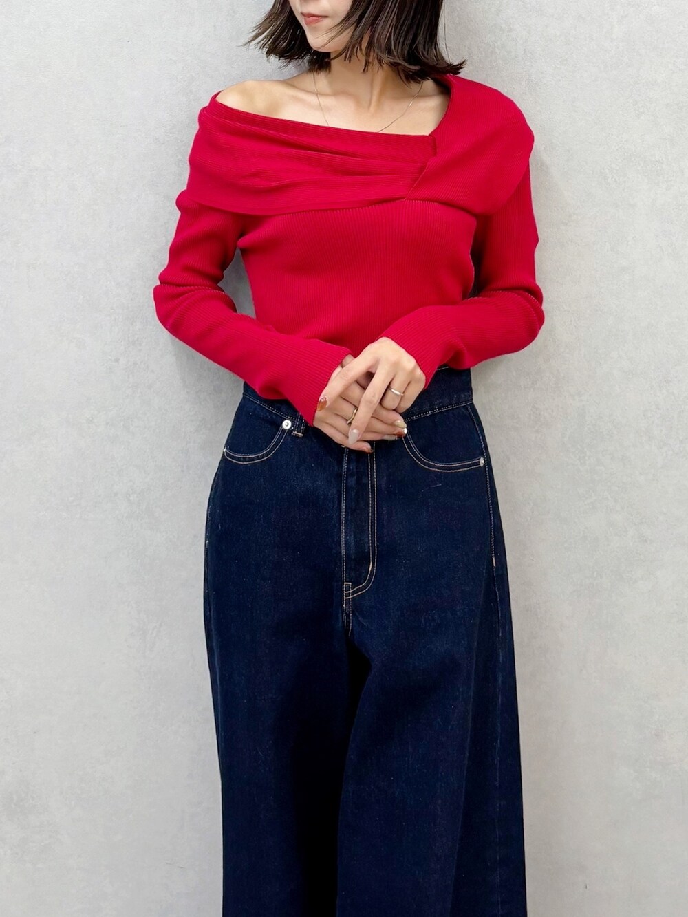 レッド系のニット/セーター、ブルー系のデニムパンツ、ブラウン系のブーツを着用したレディースの秋コーディネートの5枚目の写真