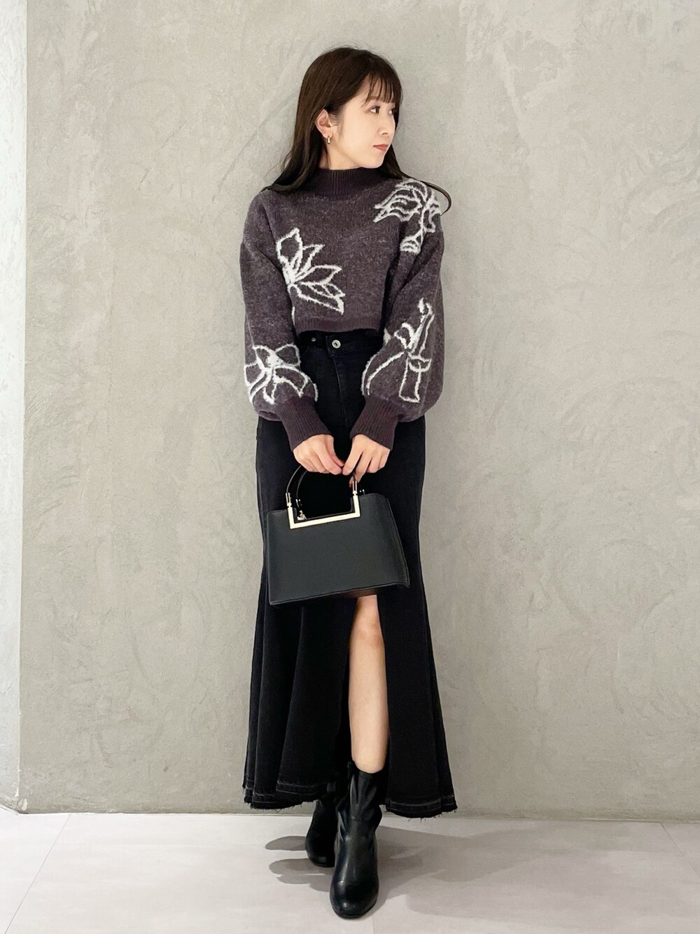 ブラック系のハンドバッグ、ブラック系のスカート、グレー系のニット/セーターを着用したレディースの秋コーディネートの6枚目の写真