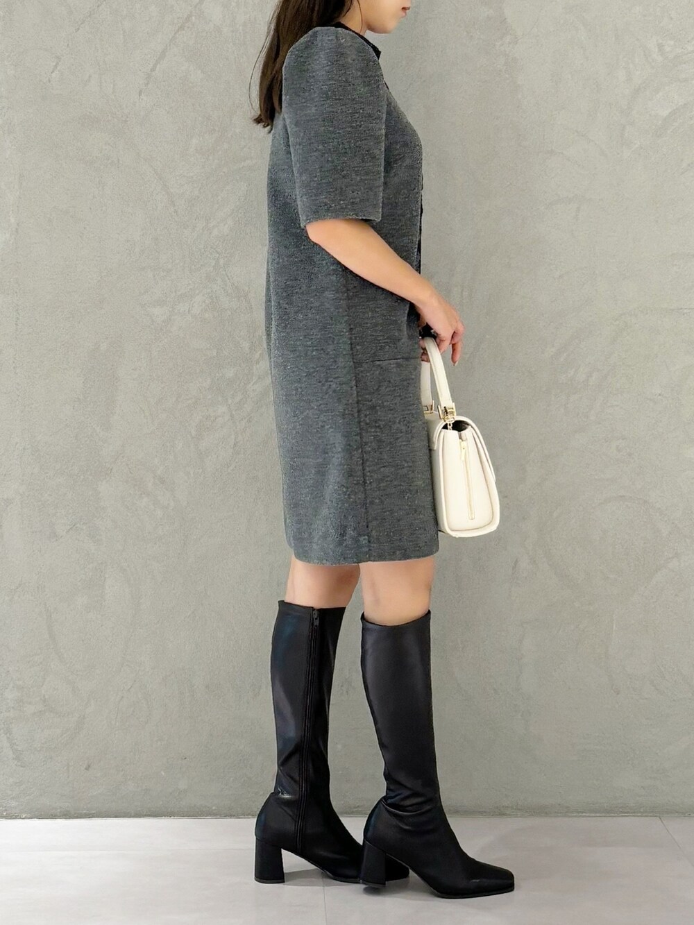 ブラック系のブーツ、ホワイト系のショルダーバッグ、グレー系のワンピースを着用したレディースの秋コーディネートの4枚目の写真