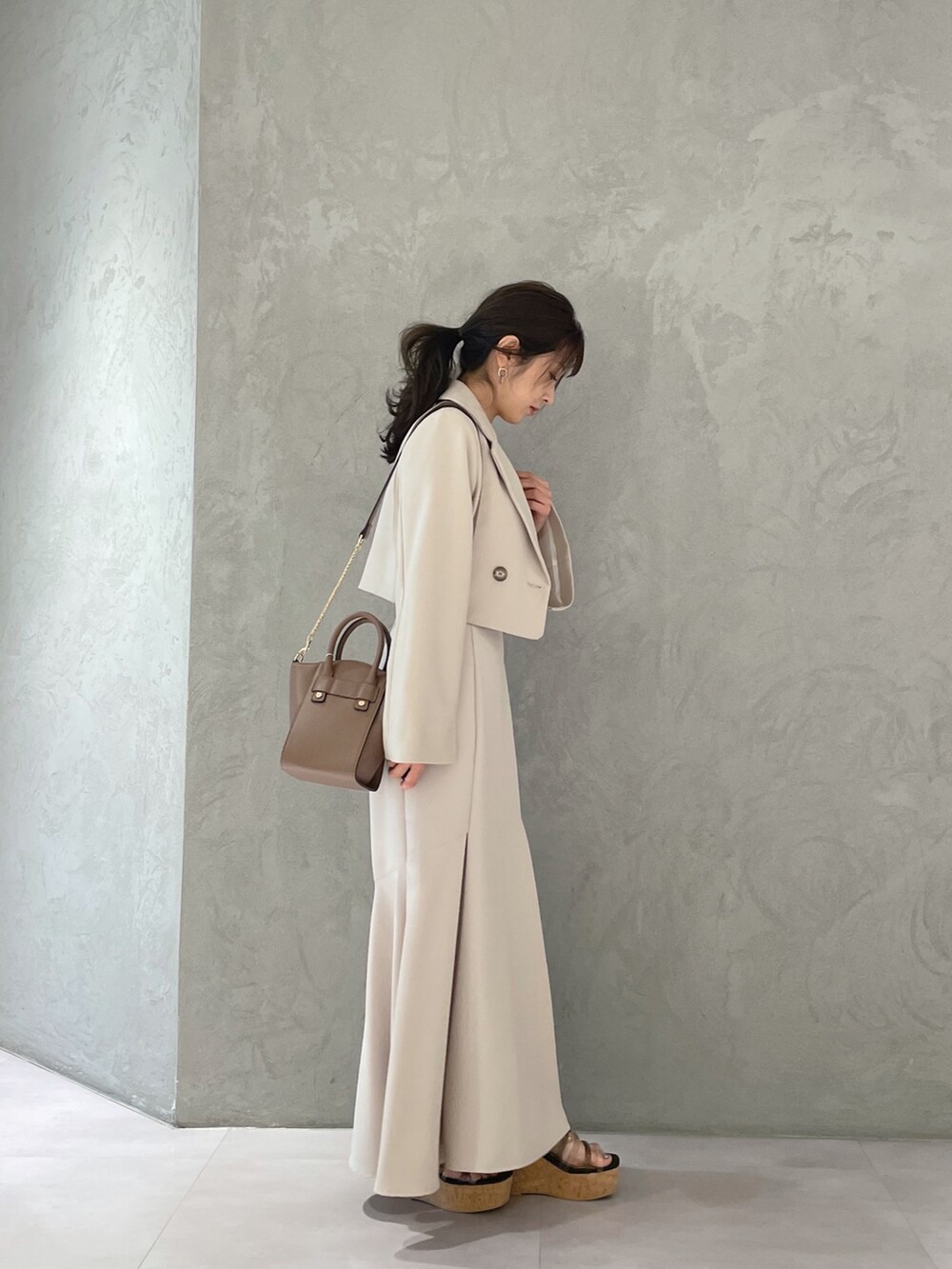 ブラック系のサンダル、ベージュ系のスカート、イエロー系のニット/セーターを着用したレディースの春コーディネートの6枚目の写真