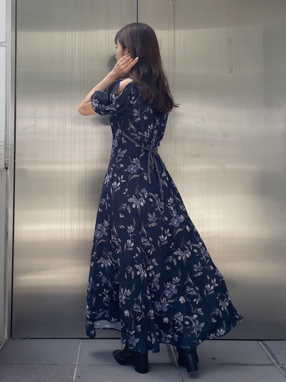 ホワイト系のハンドバッグ、ブルー系のワンピース、ブラック系のブーツを着用したレディースの夏コーディネートの2枚目の写真