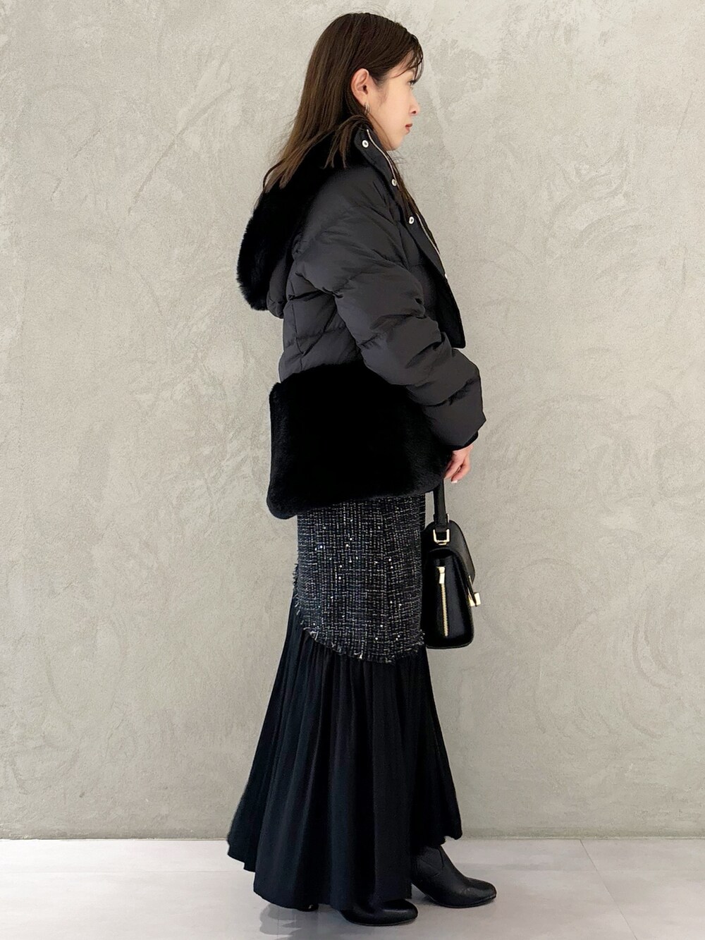 ブラック系のスカート、ブラック系のブーツ、ブラック系のショルダーバッグを着用したレディースの秋コーディネートの7枚目の写真