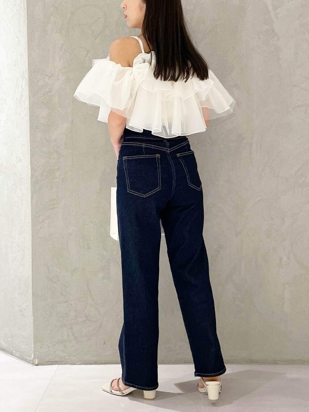 ピンク系のトートバッグ、ブルー系のデニムパンツ、ホワイト系のサンダルを着用したレディースの夏コーディネートの3枚目の写真