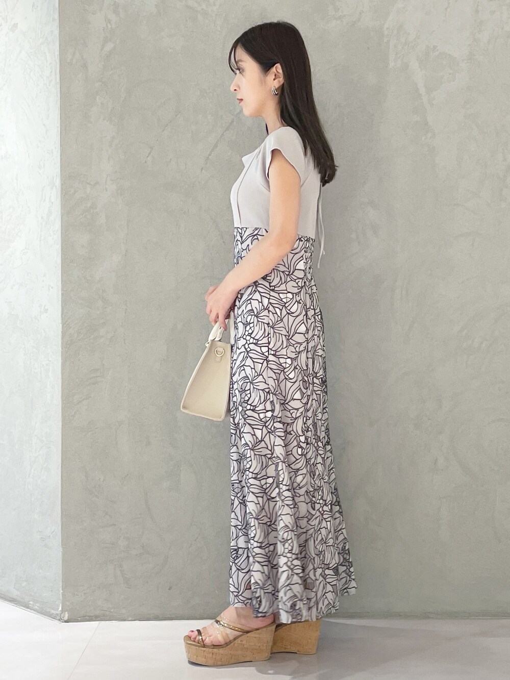 ホワイト系のショルダーバッグ、ブラウン系のサンダル、ベージュ系のワンピースを着用したレディースの春コーディネートの2枚目の写真