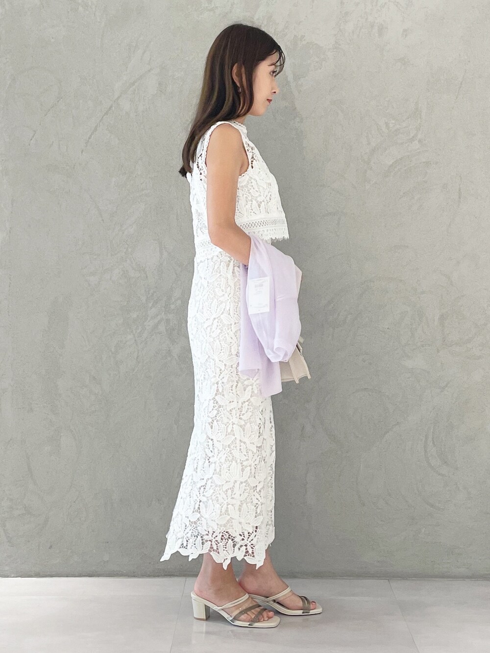 ベージュ系のショルダーバッグ、ホワイト系のサンダル、パープル系のカーディガン/ボレロを着用したレディースの夏コーディネートの2枚目の写真