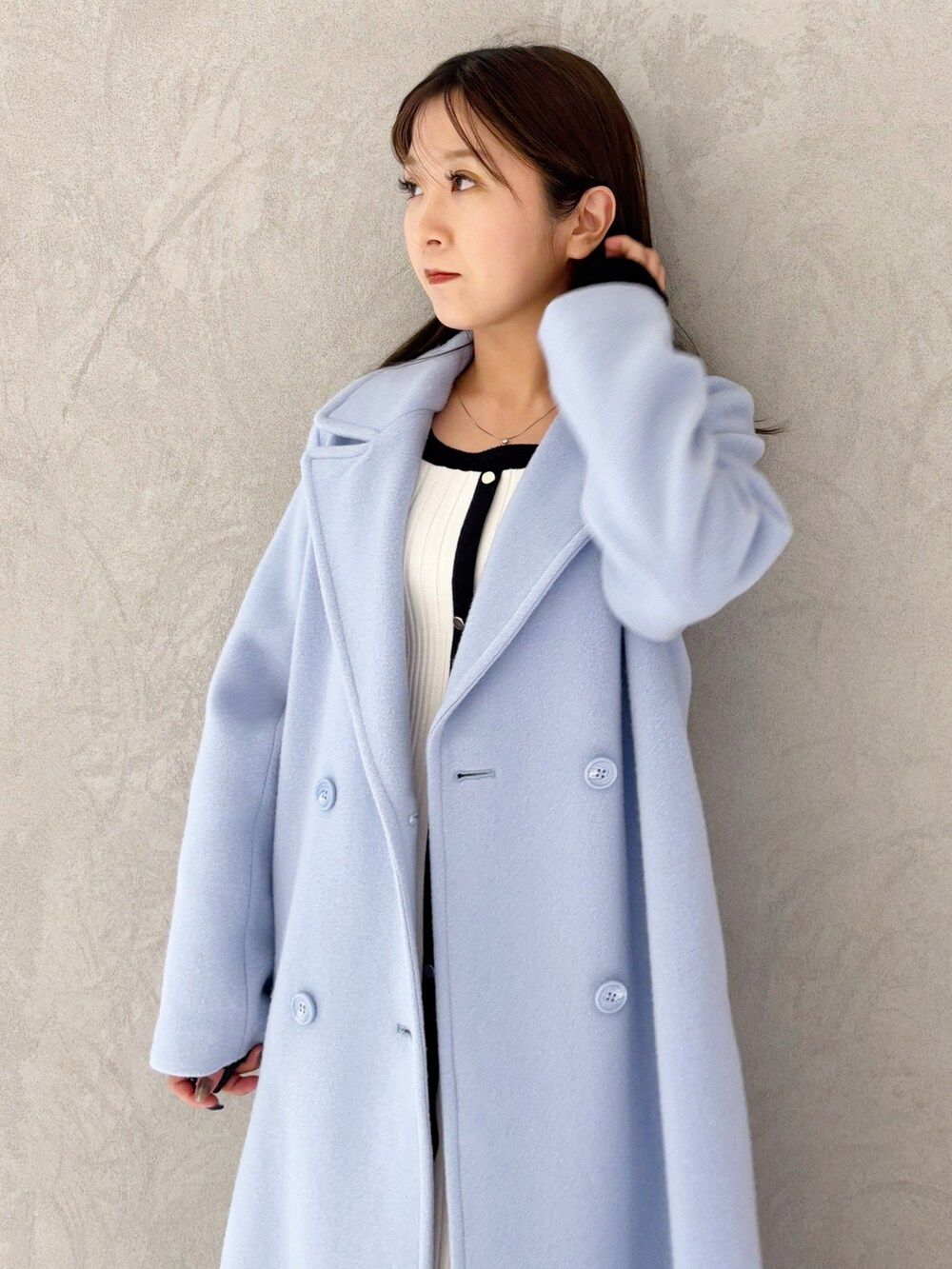 ブルー系のチェスターコート、ブラック系のブーツ、ホワイト系のワンピースを着用したレディースの冬コーディネートの2枚目の写真