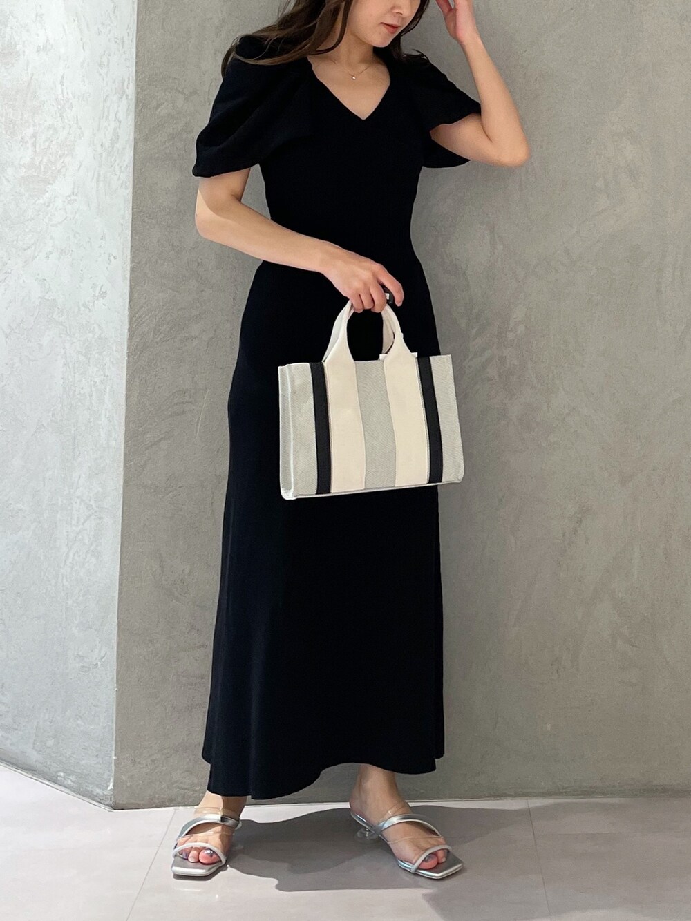 グレー系のワンピース、シルバー系のサンダル、グレー系のハンドバッグを着用したレディースの春コーディネートの3枚目の写真