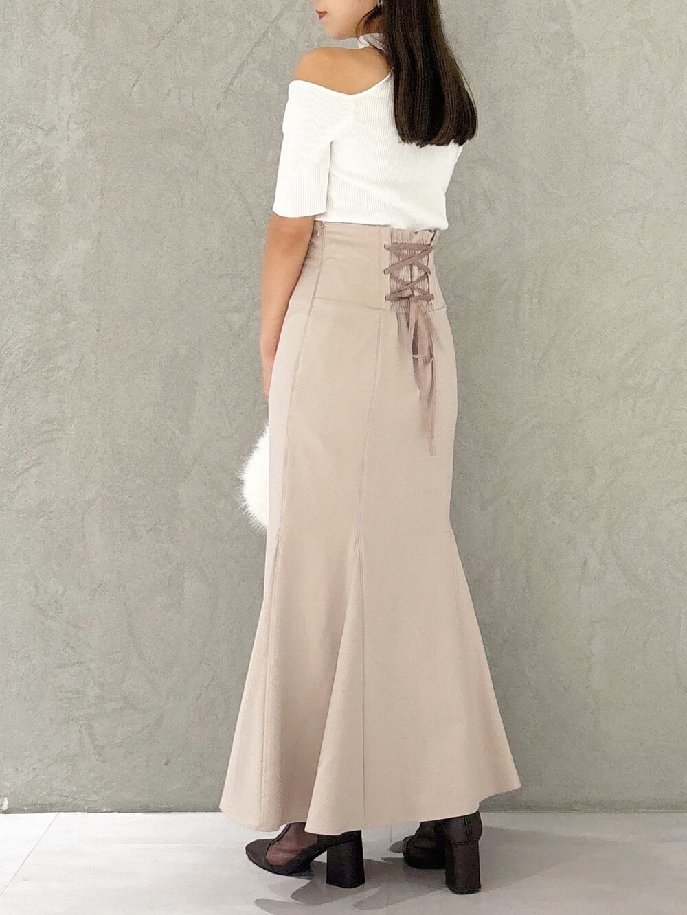 ピンク系のスカート、ブラウン系のブーツ、ホワイト系のハンドバッグを着用したレディースの秋コーディネートの4枚目の写真