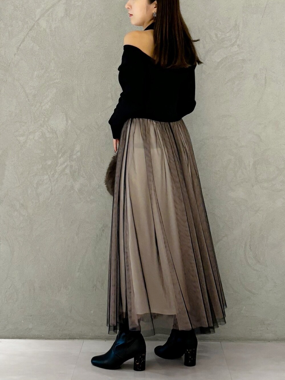 ブラック系のワンピース、ブラック系のブーツ、ブラウン系のハンドバッグを着用したレディースの秋コーディネートの2枚目の写真