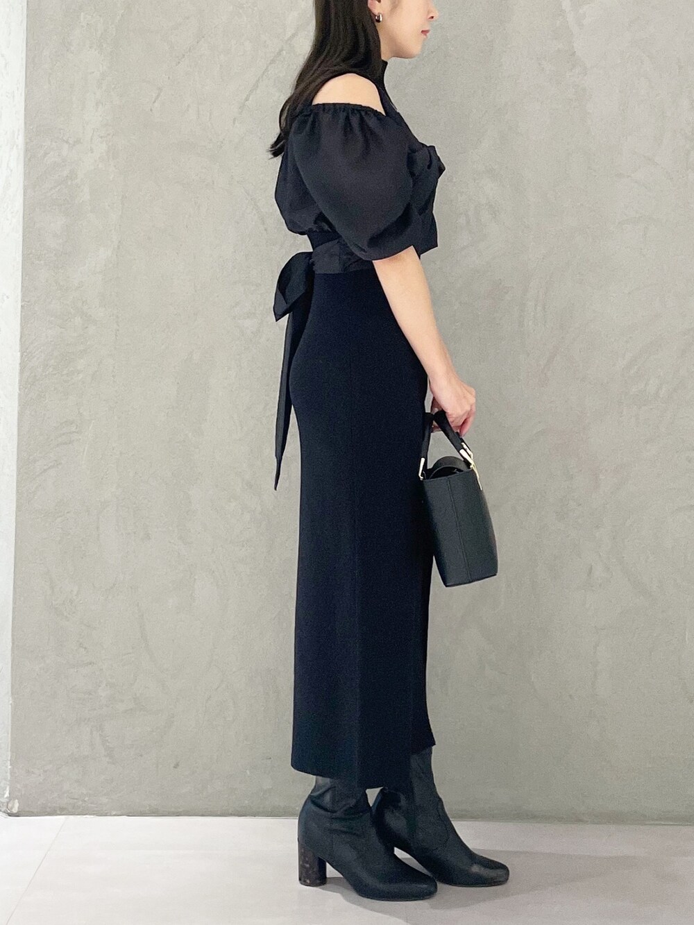 ブラック系のハンドバッグ、ブラック系のブーツ、ブラック系のワンピースを着用したレディースの春コーディネートの3枚目の写真