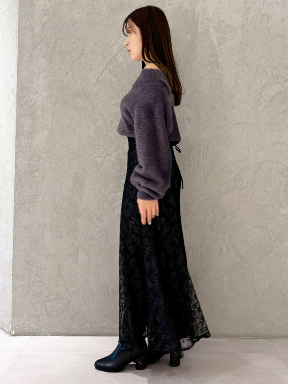 ブラック系のスカート、ブラック系のブーツ、ホワイト系のショルダーバッグを着用したレディースの冬コーディネートの3枚目の写真