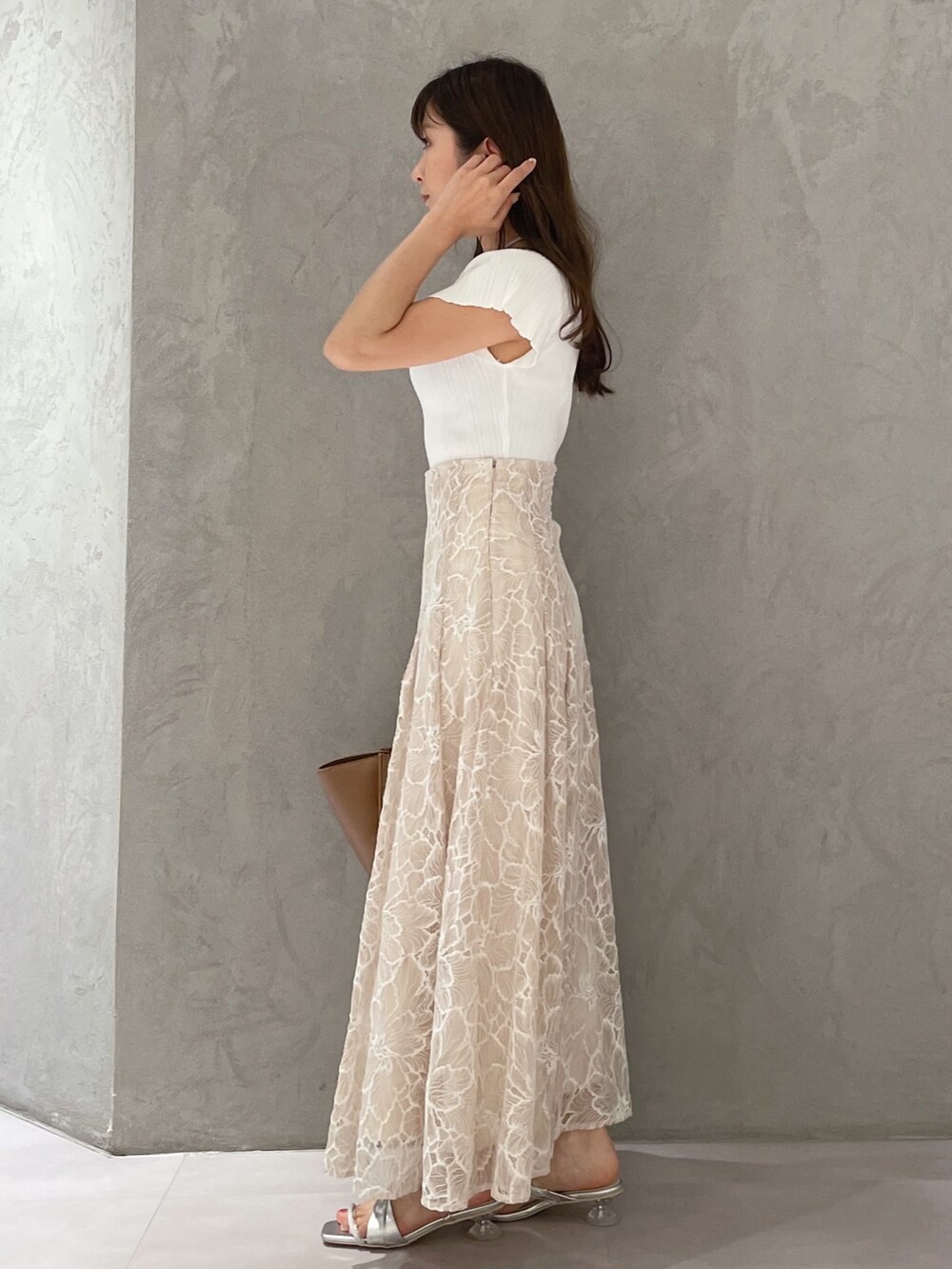 ブラウン系のトートバッグ、ホワイト系のニット/セーター、ベージュ系のスカートを着用したレディースの夏コーディネートの2枚目の写真