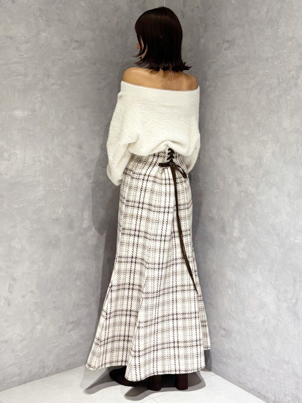 ホワイト系のスカート、ホワイト系のニット/セーター、ブラウン系のブーツを着用したレディースの秋コーディネートの2枚目の写真