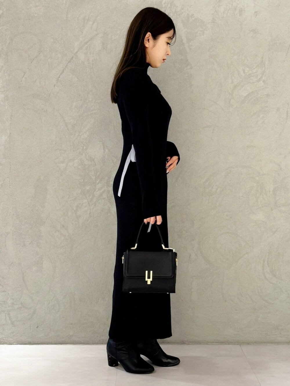 ブルー系のワンピース、ブラック系のブーツ、ブラック系のショルダーバッグを着用したレディースの冬コーディネートの3枚目の写真