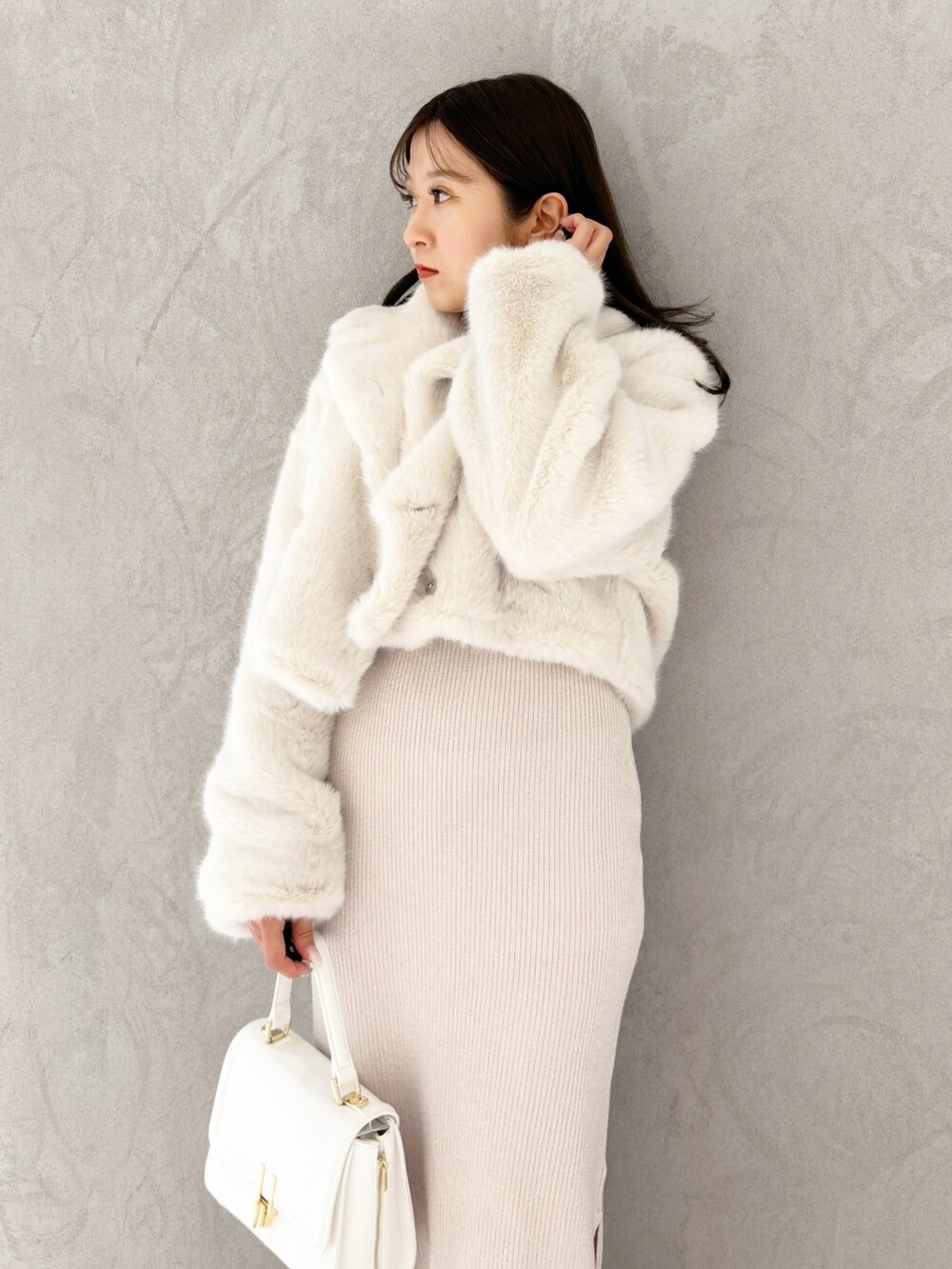 ホワイト系のワンピース、ブラック系のブーツ、ホワイト系のハンドバッグを着用したレディースの冬コーディネートの5枚目の写真