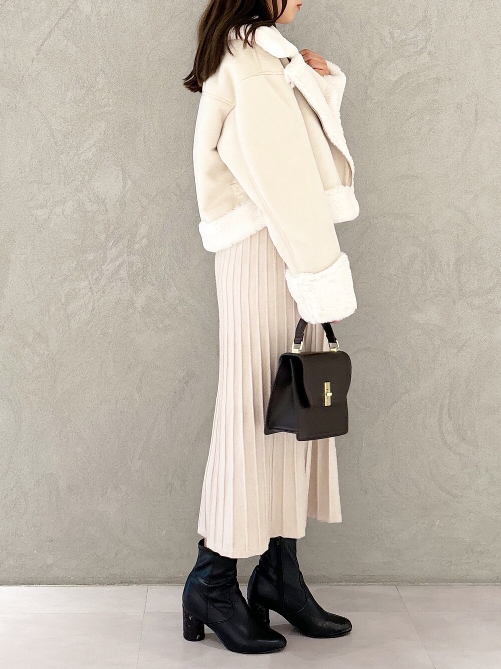 ホワイト系のワンピース、ブラック系のブーツ、ホワイト系のムートンコートを着用したレディースの秋コーディネートの4枚目の写真