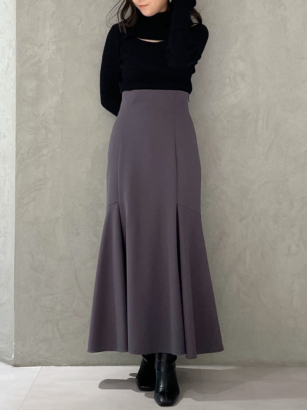 グレー系のスカート、グレー系のニット/セーター、ブラック系のブーツを着用したレディースの冬コーディネートの6枚目の写真