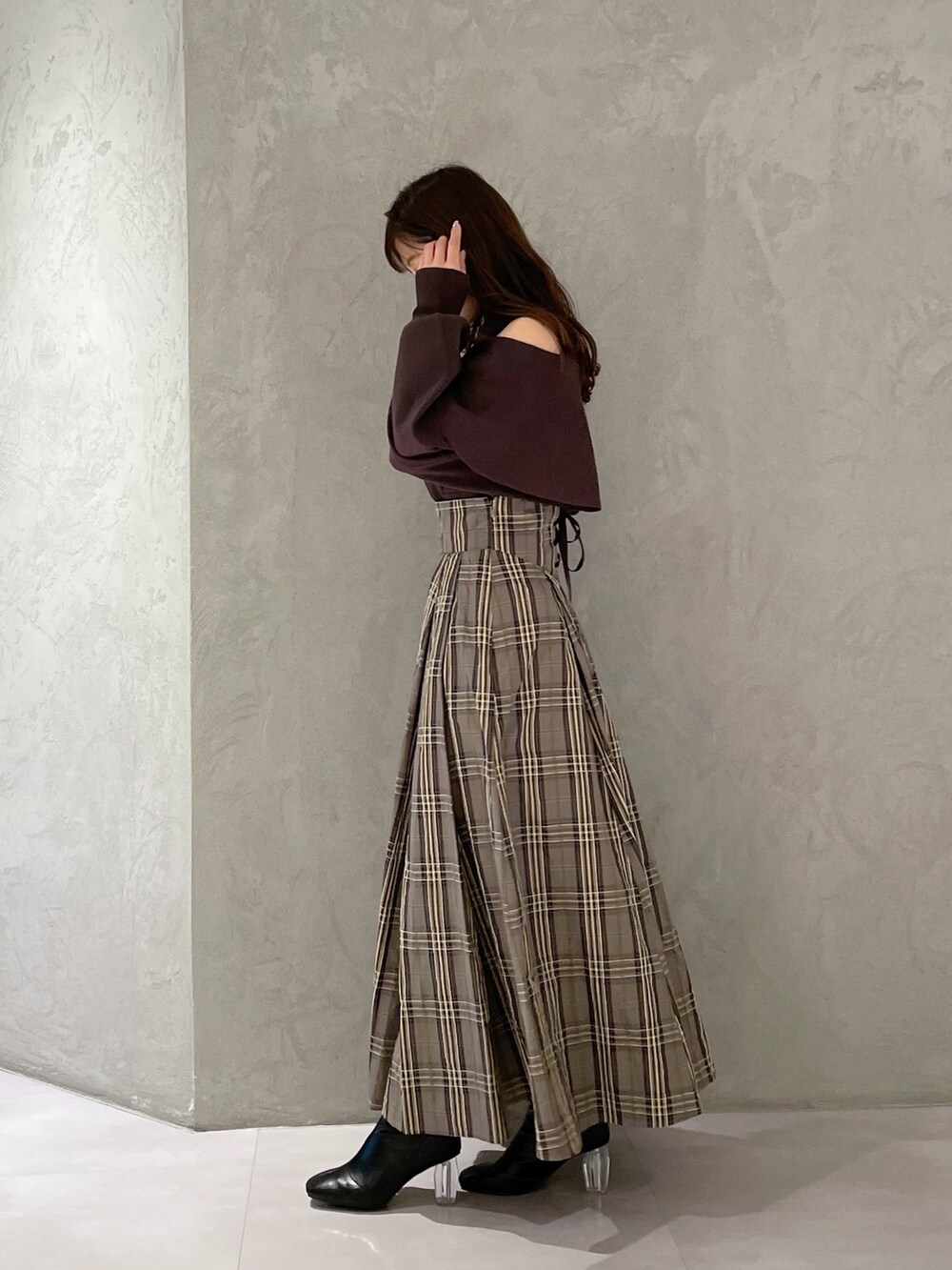 ベージュ系のスカート、ブラウン系のニット/セーター、ブラック系のブーツを着用したレディースの秋コーディネートの6枚目の写真