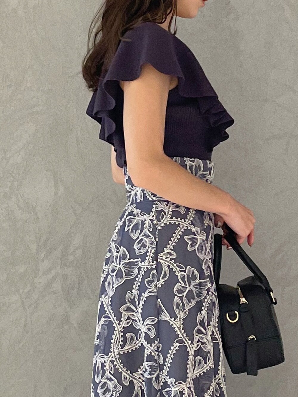 グレー系のスカート、グレー系のニット/セーター、ブラック系のサンダルを着用したレディースの夏コーディネートの3枚目の写真