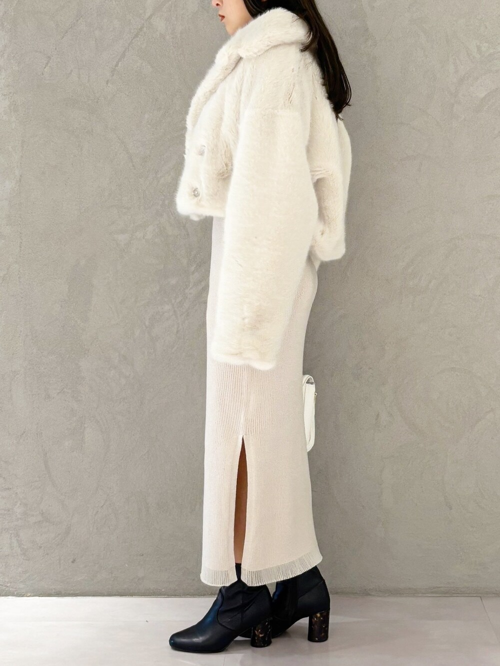 ホワイト系のワンピース、ブラック系のブーツ、ホワイト系のハンドバッグを着用したレディースの冬コーディネートの6枚目の写真