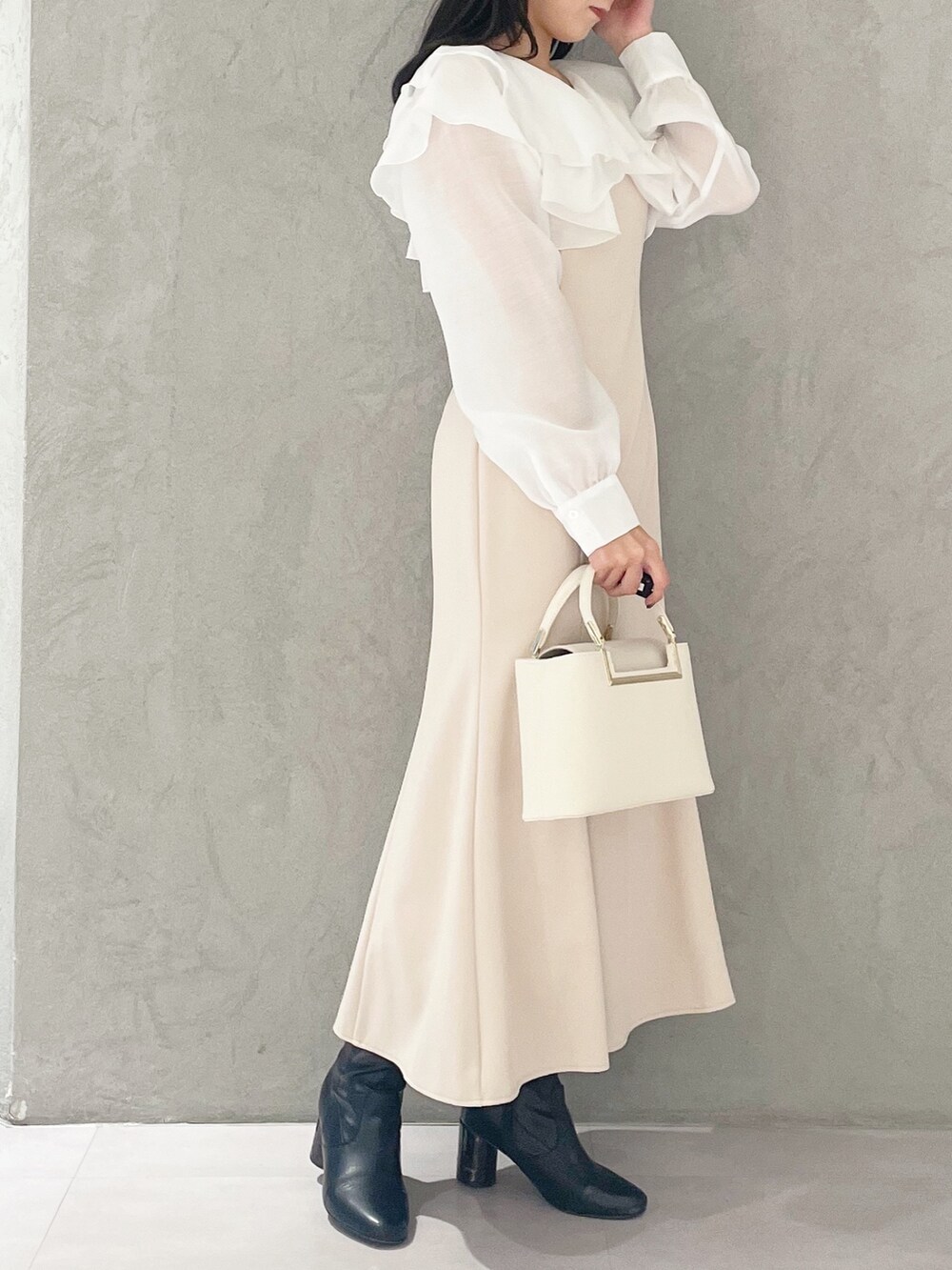 ベージュ系のワンピース、ホワイト系のハンドバッグ、ブラック系のブーツを着用したレディースの冬コーディネートの4枚目の写真