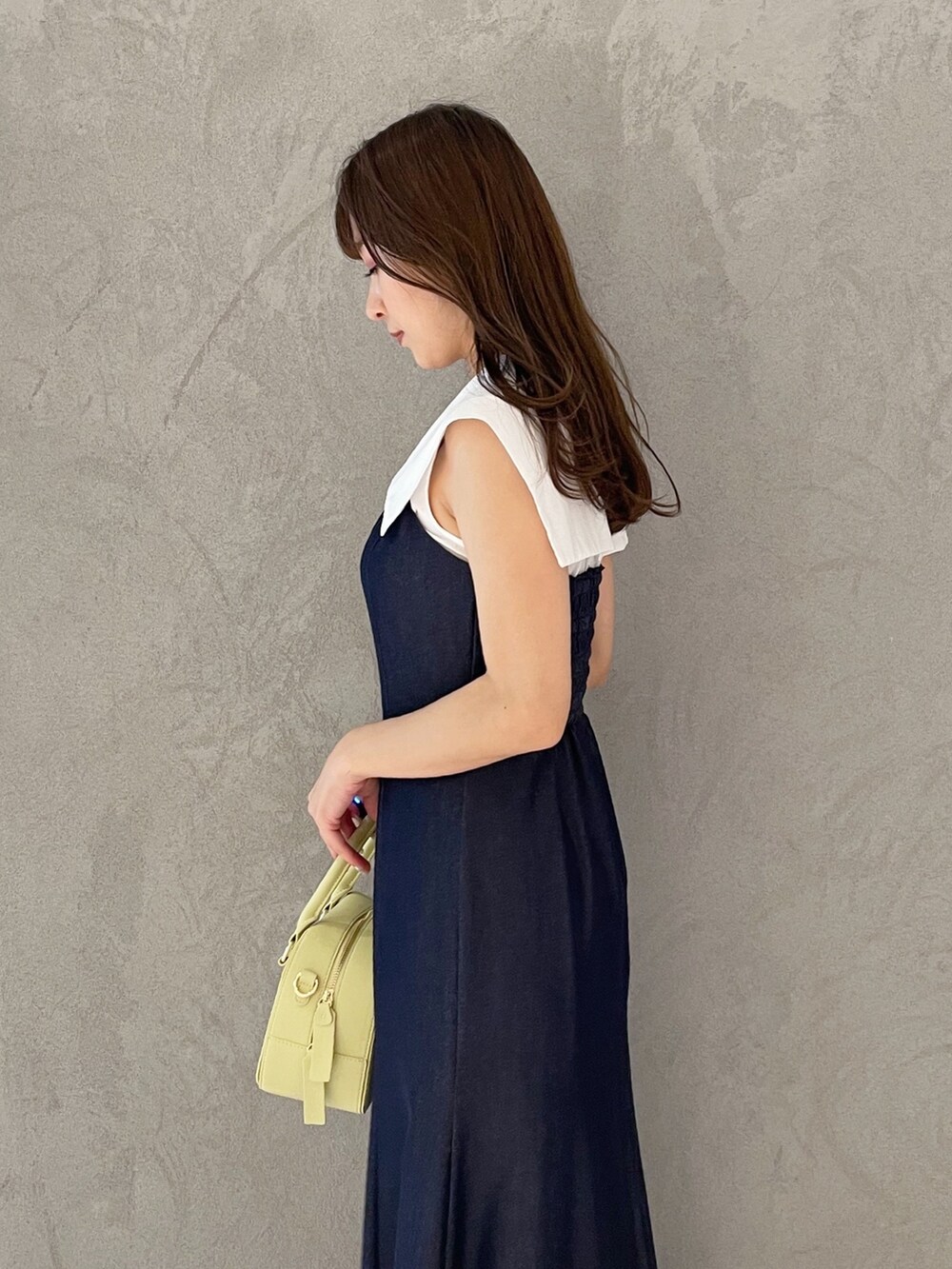 ブルー系のワンピース、イエロー系のボストンバッグ、ブラック系のサンダルを着用したレディースの春コーディネートの5枚目の写真